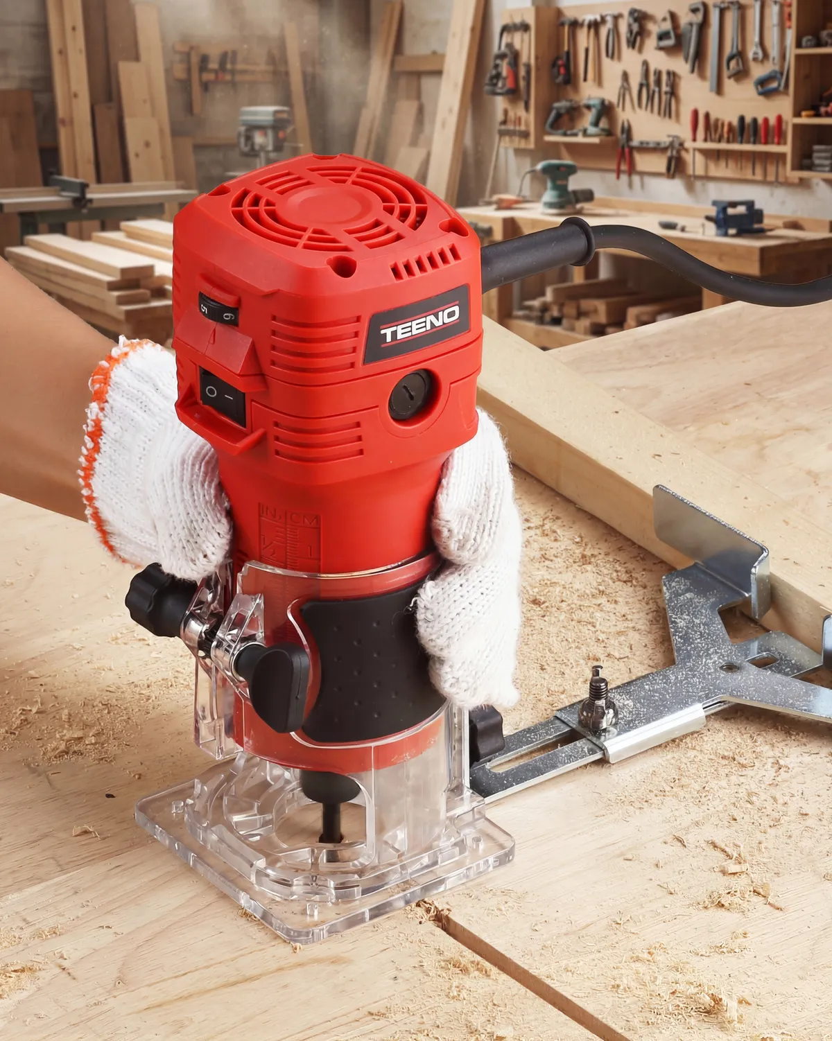 Red TEENO palm router with a clear base standing on a pine board in a workshop